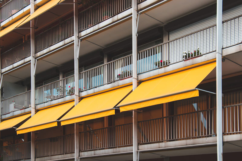 Immeubles avec des appartements à balcons avec des stores bannes jaunes